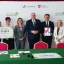 grupa osob stoi na tle scianki
